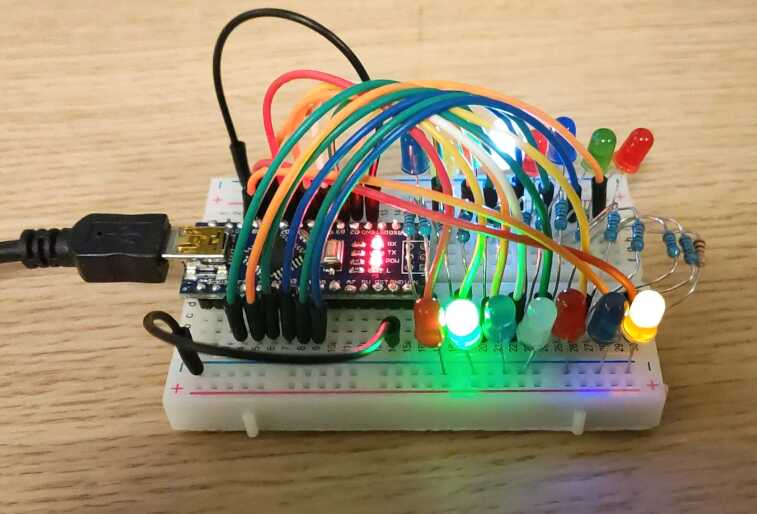 A breadboard holding an Arduino and several other components including a range of coloured LEDs, some of which are on.